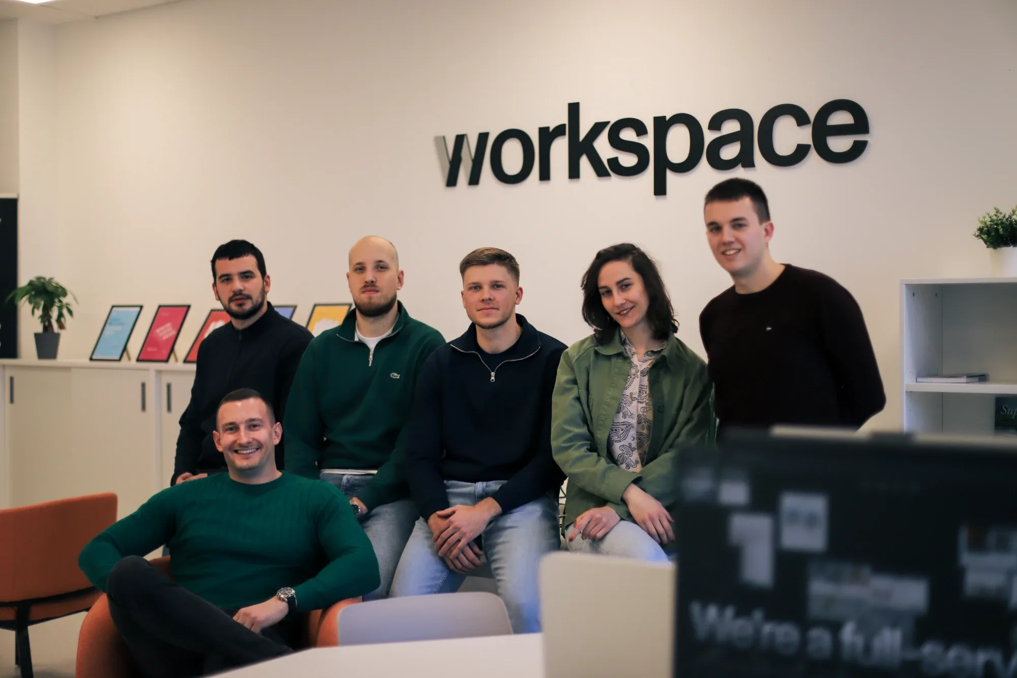 The Workspace team in front of the Workspace logo in our office.